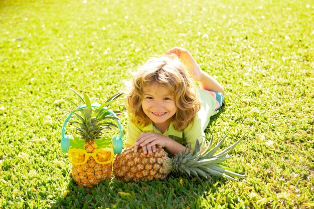 Enfant garçon tenant un ananas posant fond de nature d'été avec copie espace fruits sains pour chi