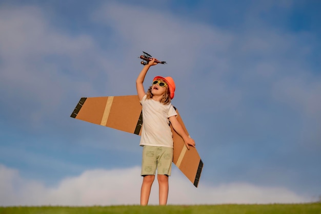 Enfant garçon tout-petit jouant avec un avion jouet et rêvant de l'avenir Heureux garçon pilote jouer avec un avion à l'extérieur