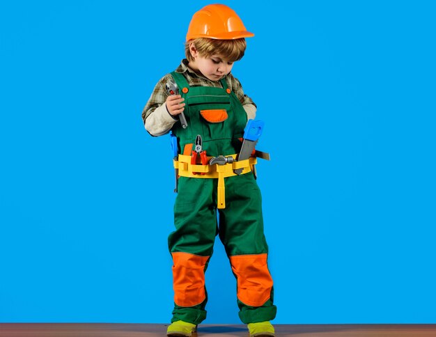 enfant garçon en uniforme de constructeur et casque avec outils de réparation, jeu d'enfant, petit garçon joue à un ouvrier du bâtiment.