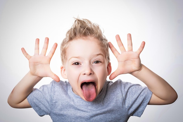 L'enfant Gâté Fait Des Grimaces Le Garçon Montre Sa Langue