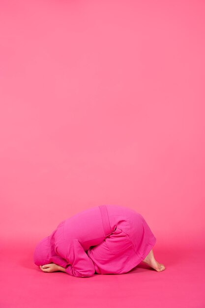 Enfant à genoux isolé sur fond rose