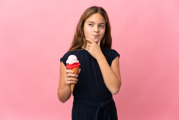 Enfant avec une glace au cornet sur rose isolé ayant des doutes