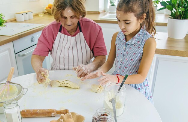 L'enfant et la grand-mère dans la cuisine préparent la pâte dans la cuisine Mise au point sélective Nourriture