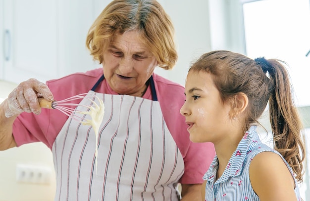 L'enfant et la grand-mère dans la cuisine préparent la pâte dans la cuisine Mise au point sélective