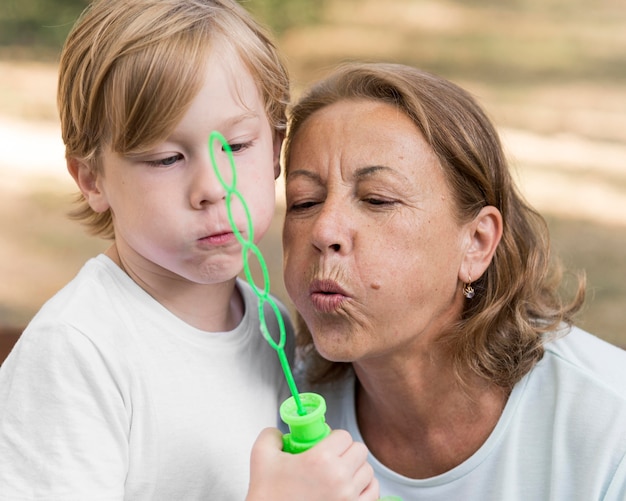 Enfant et grand-mère faisant des ballons de savon