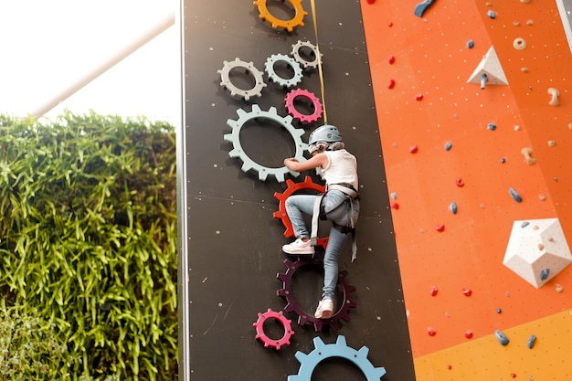 Photo enfant grimpant sur un mur dans un centre d'amusement formation d'escalade pour enfants petite fille en tenue d'escalade habillée grimper haut loisirs actifs extrêmes pour les enfants