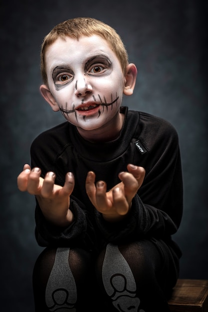 Enfant habillé en squelette dans une pose effrayante. costume d'halloween, tourné en studio