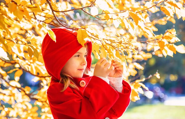 Enfant en habit rouge avec des feuilles d&#39;automne. Aime l&#39;automne. Mise au point sélective.