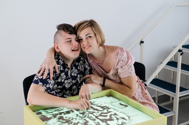 Enfant handicapé faisant une activité sensorielle avec réhabilitation de sable