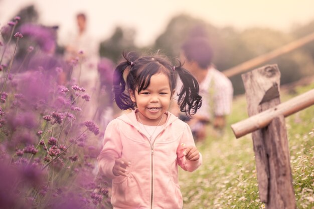 Enfant heureuse petite fille courir et s&#39;amuser dans le champ de fleurs violettes