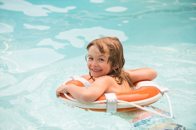 Enfant heureux avec anneau de natation. Fête d'été dans la piscine. Enfant dans la piscine. Garçon s'amusant au parc aquatique.