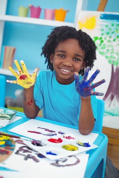 Enfant heureux, appréciant la peinture avec ses mains