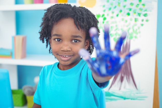 Enfant heureux, appréciant la peinture avec ses mains