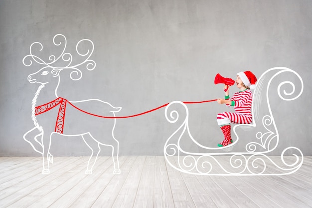 Enfant heureux au moment de Noël. Enfant drôle jouant à la maison