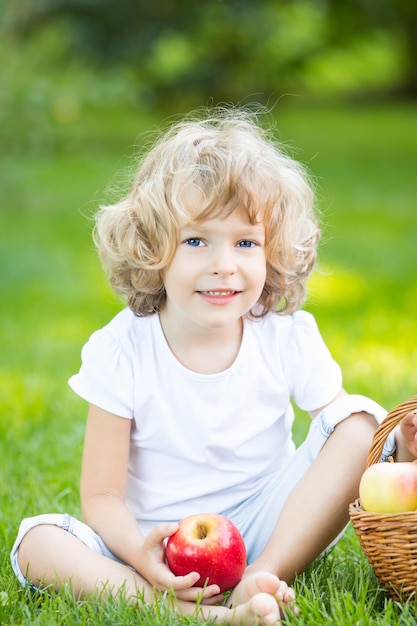 Enfant heureux ayant un pique-nique à l'extérieur dans le parc du printemps