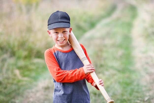 Un enfant heureux avec une batte de baseball sur le concept de la nature dans le parc