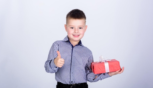 Enfant heureux avec boîte cadeau Noël petit garçon avec cadeau Saint Valentin Fête d'anniversaire Shopping Jour de Noël Nouvel an style d'affaires Enfance heureuse enfant heureux avec le geste du pouce vers le haut