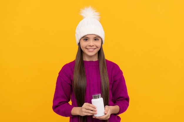 Enfant heureux en chapeau d'hiver avec pilulier, santé.