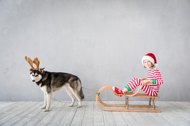 enfant heureux et chien la veille de noël enfant et animal de compagnie vêtus d'un chapeau de père noël