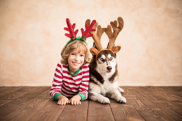 enfant heureux et chien la veille de noël enfant et animal de compagnie vêtus d'un chapeau de père noël