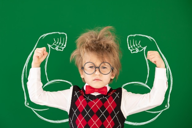 Enfant heureux en classe contre le tableau vert