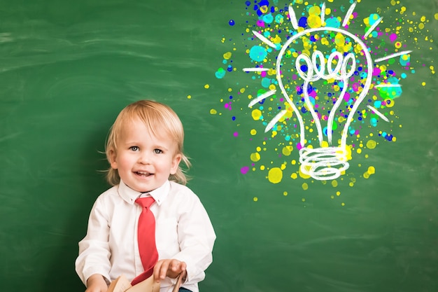 Enfant heureux en classe. Enfant drôle contre le tableau. Retour à l'école. Notion d'éducation