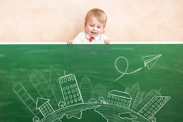 Enfant heureux en classe. Enfant drôle contre le tableau. Retour à l'école. Notion d'éducation