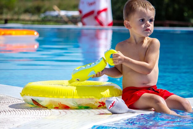 Enfant heureux dans la piscine jouant avec un pistolet à eau.