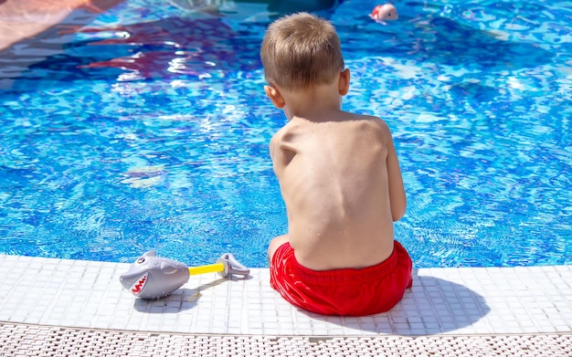 Enfant heureux dans la piscine jouant avec un pistolet à eau.