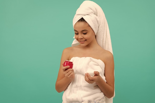 Un enfant heureux dans la tour de bain tient la beauté de la crème pour le visage