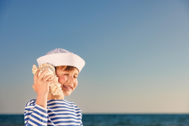 Un enfant heureux écoute un coquillage sur la plage