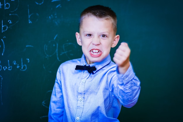 Un enfant heureux enfant debout au tableau dans la classe d'école à la leçon