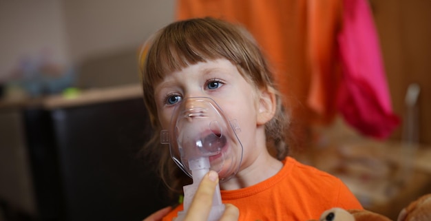 L'enfant heureux fait l'inhalation à la maison pour