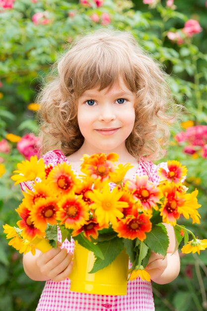 Enfant heureux avec des fleurs à l'extérieur dans le jardin de printemps