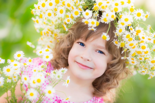 Enfant heureux avec des fleurs de marguerite à l'extérieur dans le jardin de printemps