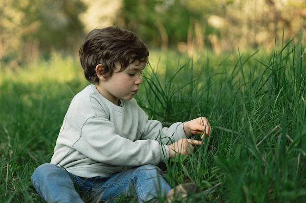 L'enfant heureux gai joue sur le pré vert