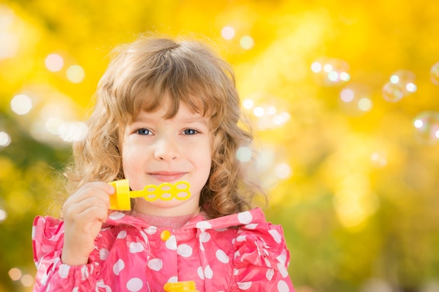 Enfant heureux jouant dehors en parc d'automne