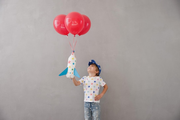 Enfant heureux jouant avec une fusée jouet à la maison Enfant se faisant passer pour un astronaute Imagination et concept de rêve pour enfants