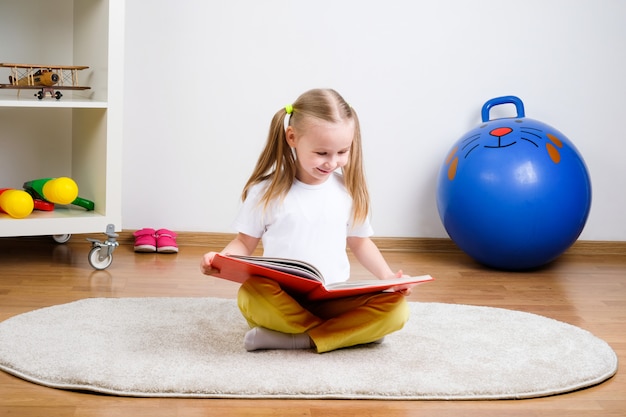 Enfant heureux lit un livre sur le tapis