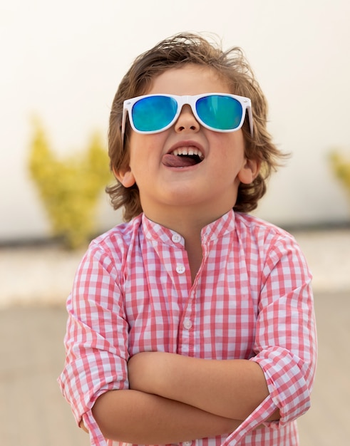 Enfant heureux avec des lunettes de soleil dans le jardin