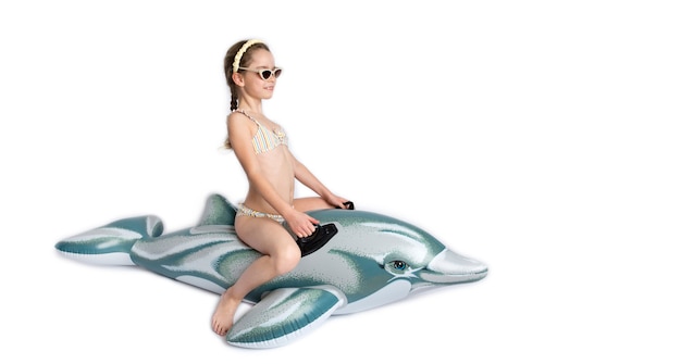 Enfant heureux en maillot de bain sur un dauphin gonflable. Photographie de studio sur fond blanc. Pandémie de coronavirus et concept de mode de vie sain. photo de haute qualité