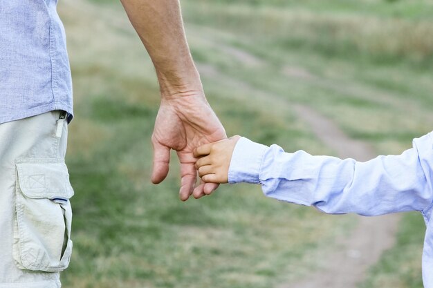 Photo un enfant heureux et les mains des parents sur la nature dans le parc voyage