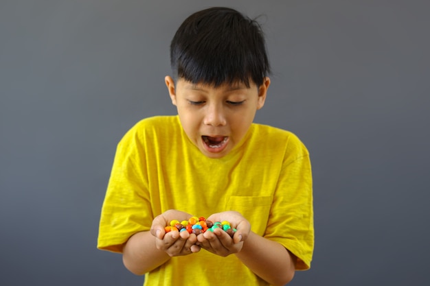 Enfant heureux avec les mains pleines de bonbons colorés assortis