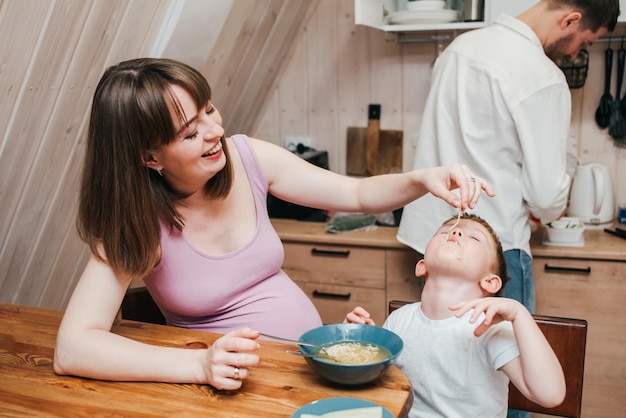 Un enfant heureux mange des pâtes dans la cuisine avec sa famille