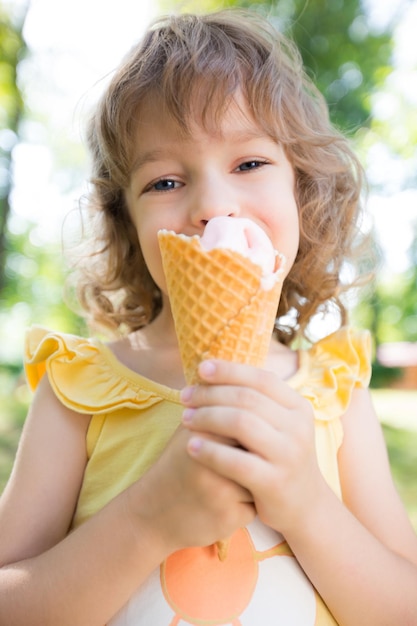 Enfant heureux mangeant de la glace à l'extérieur dans le parc d'été