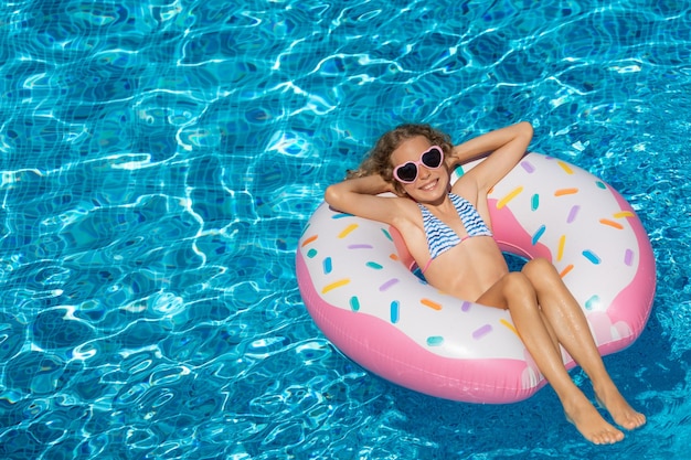 Enfant heureux nageant dans la piscine extérieure