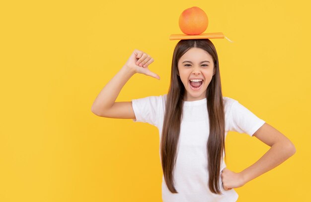 Enfant heureux avec pamplemousse et livre sur fond jaune vitamine