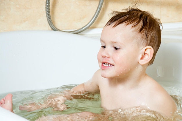 Enfant heureux petite fille se baigne dans un bain moussant se lave le visage Le concept d'hygiène des enfants éclabousse la joie de rire s'amuser Mode de vie familial