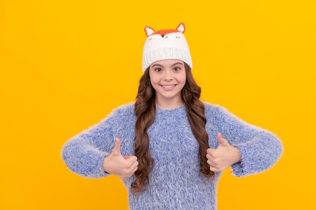 Enfant heureux en pull et chapeau sur fond jaune hiver