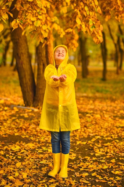 Un enfant heureux qui attrape des gouttes de pluie dans le parc d'automne